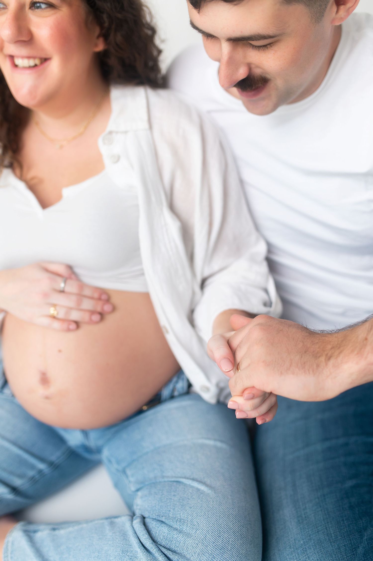 Close-up series of loving couple's hands cradling pregnant belly in studio setting.