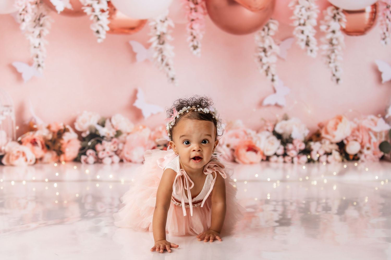Cake smash photography session with pink balloons and floral decorations.