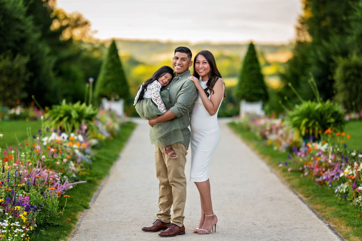 Couple poses playfully on garden path lined with colorful summer flowers.