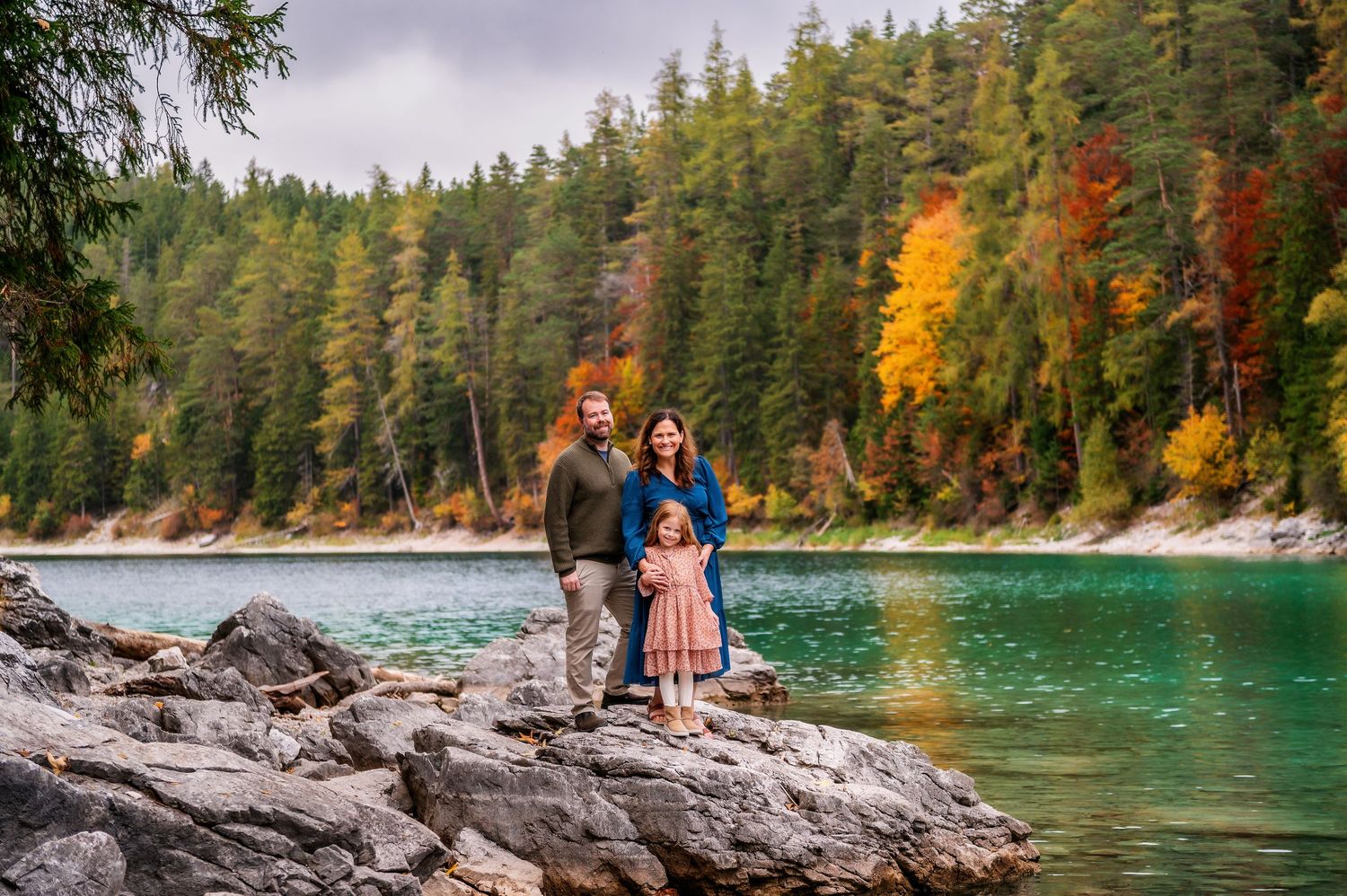 Scenic mountain lake surrounded by evergreen forest with turquoise waters and rocky shoreline in autumn.