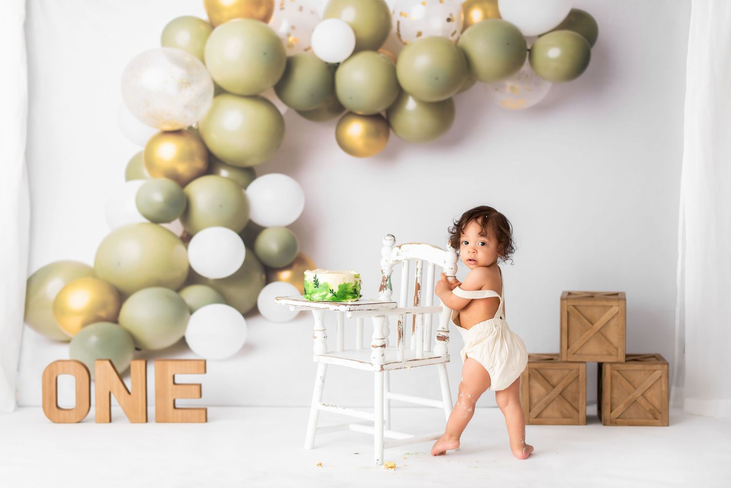 Professional photography setup with balloon arch and wooden ONE sign.