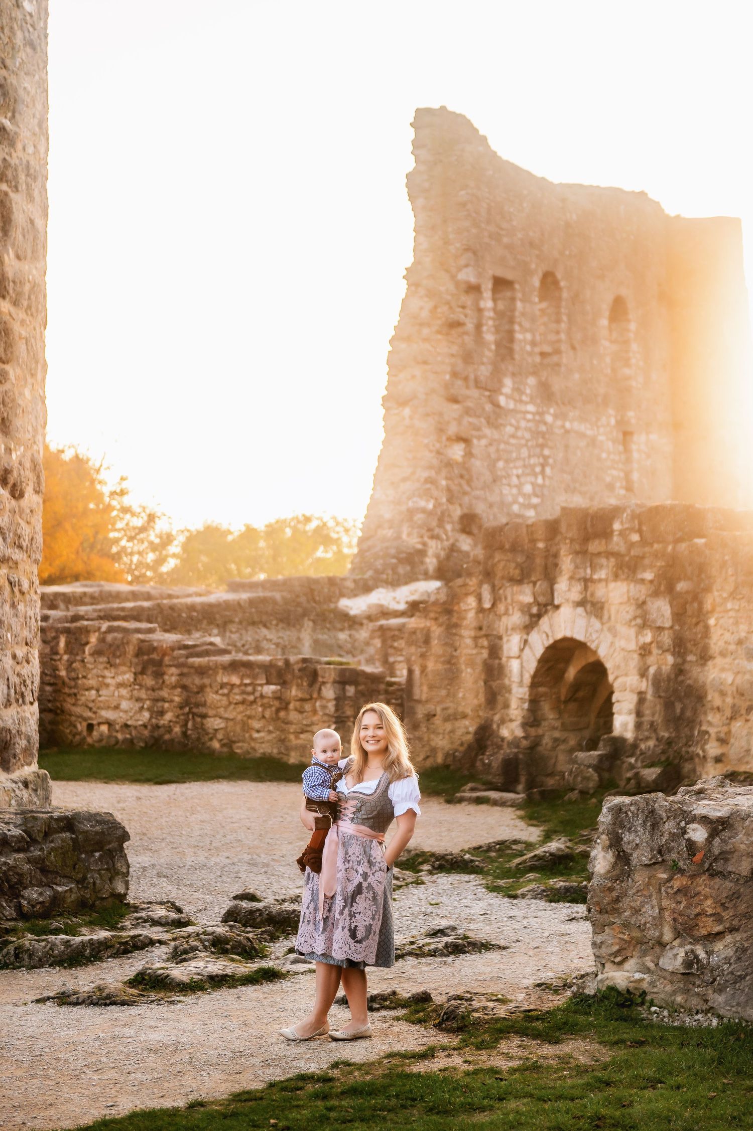 A person stands among ancient castle ruins during sunset.