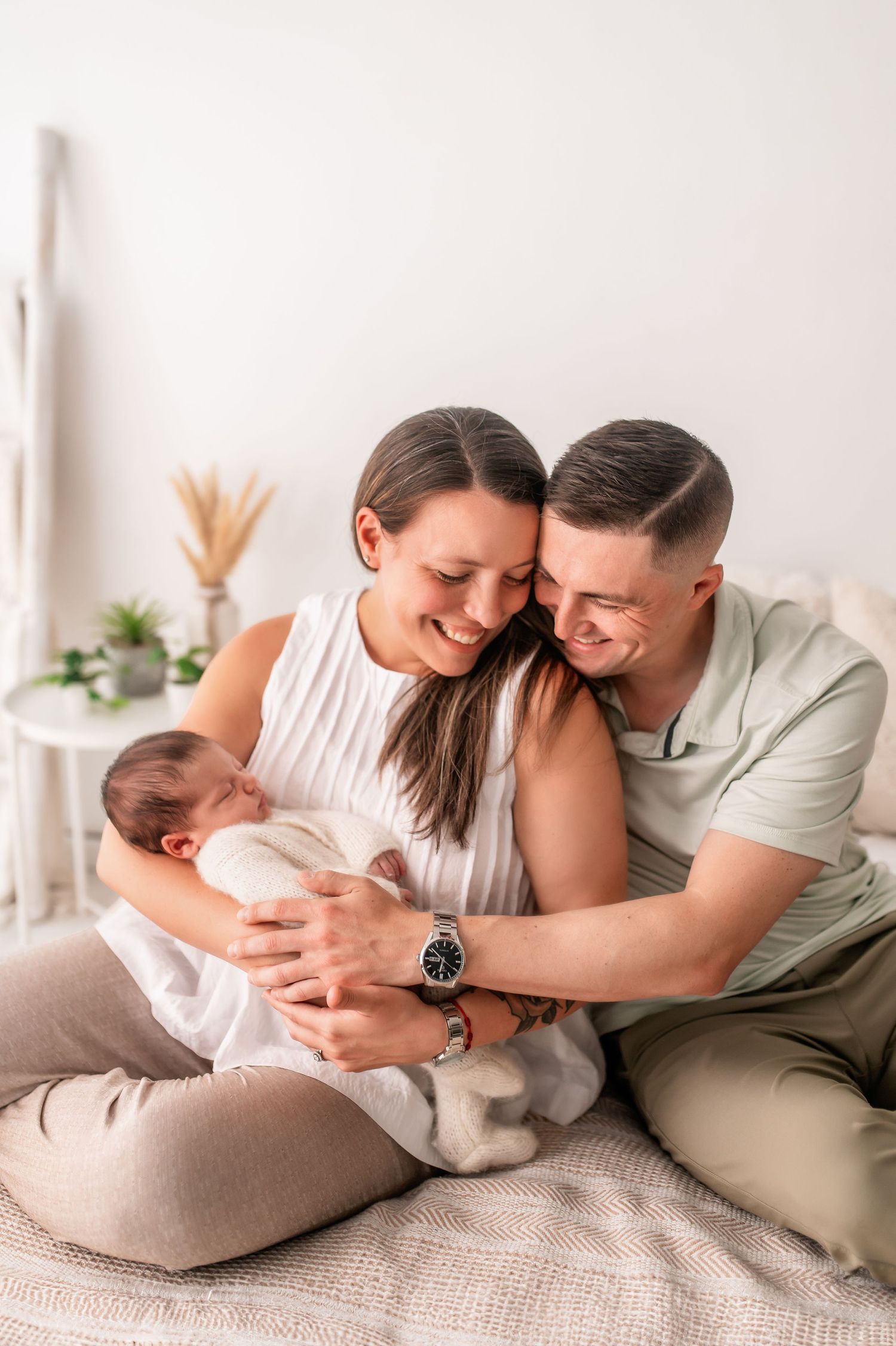 Intimate family moment captured on cream bedding with soft natural lighting.