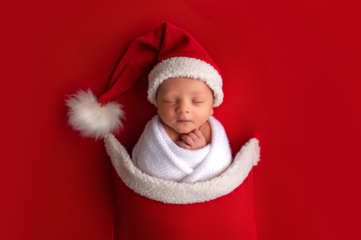 Collection of newborn photos featuring baby in white winter accessories against red background.