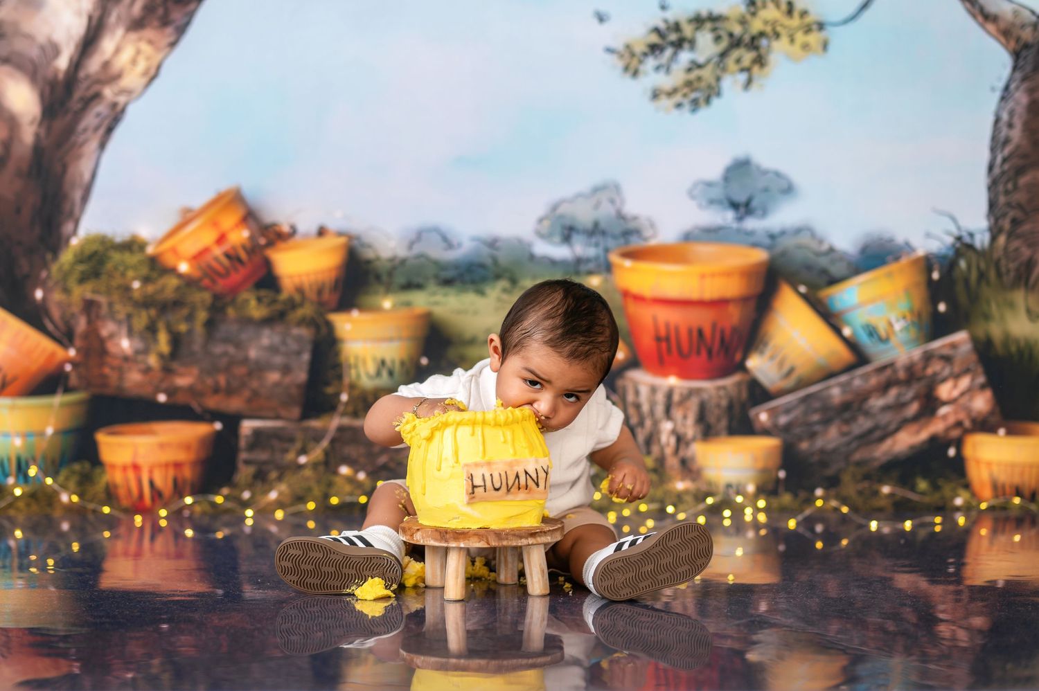 Magical honey pot themed first birthday photo shoot with string lights and woodland backdrop.