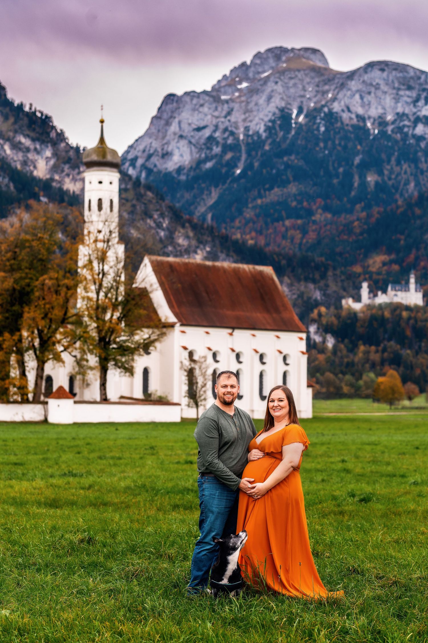 Beautiful rustic white church nestled in a green meadow with majestic Alps mountains in Bavaria during autumn.