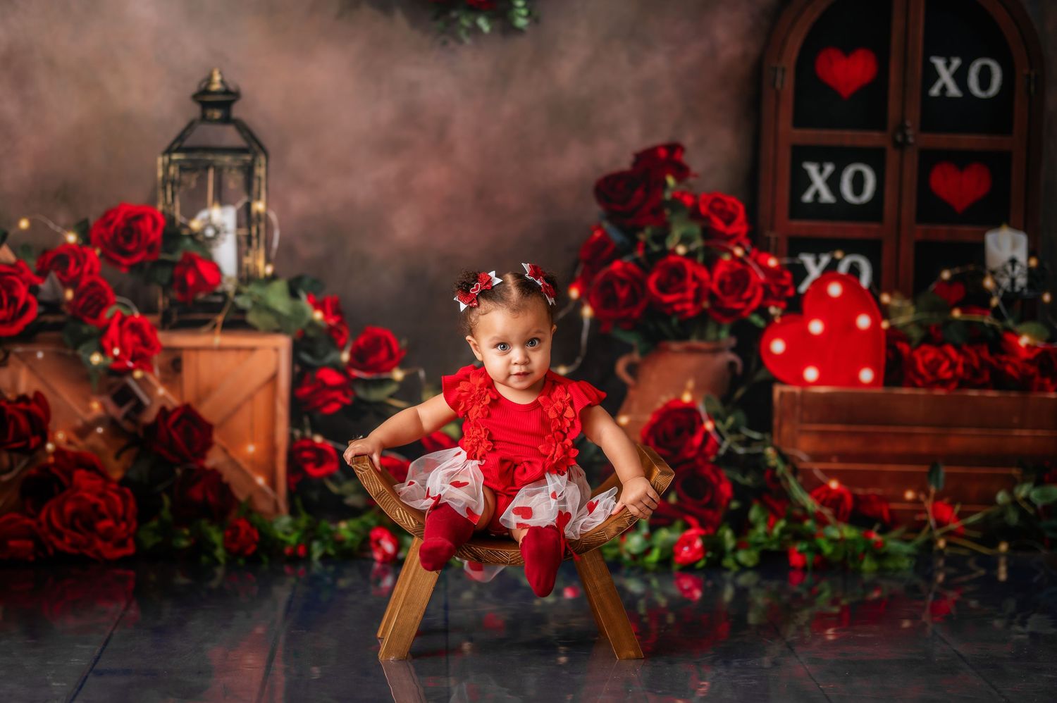 Valentine's themed cake smash photography setup with red roses and decorative elements against dark background.