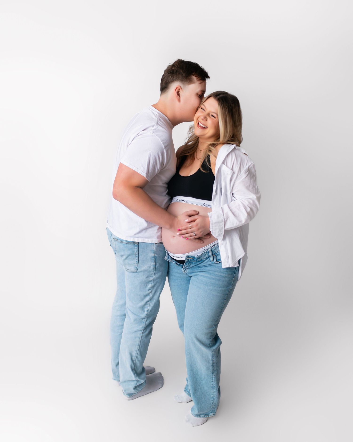 Intimate couple moment captured during studio maternity photography session.