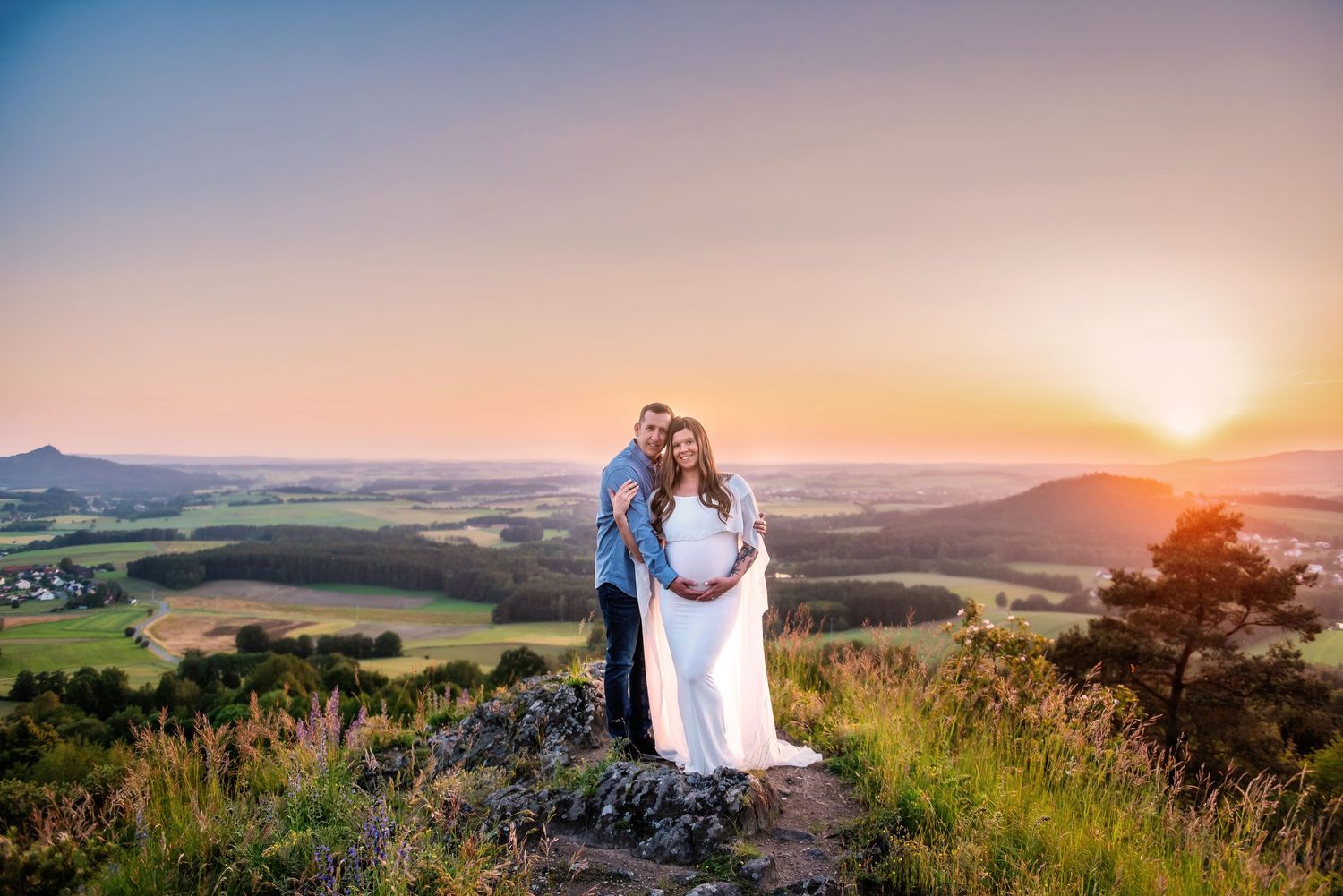 Romantic sunset maternity photoshoot with rolling hills and mountains in background.