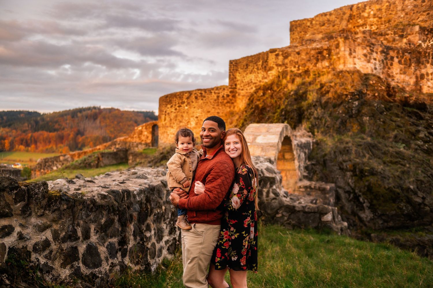Family stands together at historic castle ruins during golden hour.