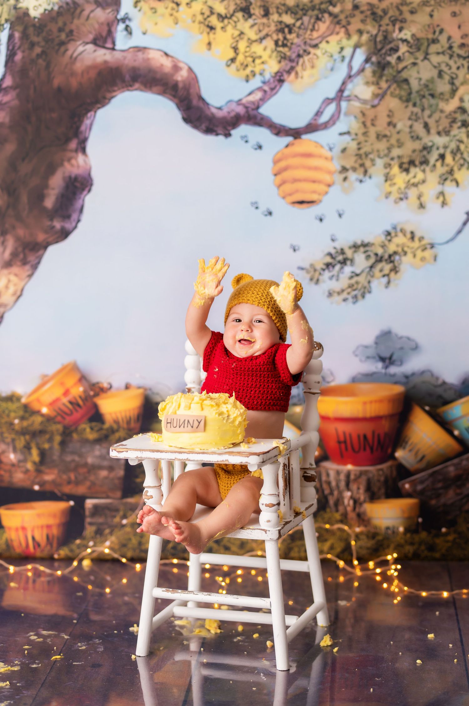 Winnie the Pooh themed cake smash photo setup with honey pots and whimsical forest backdrop.