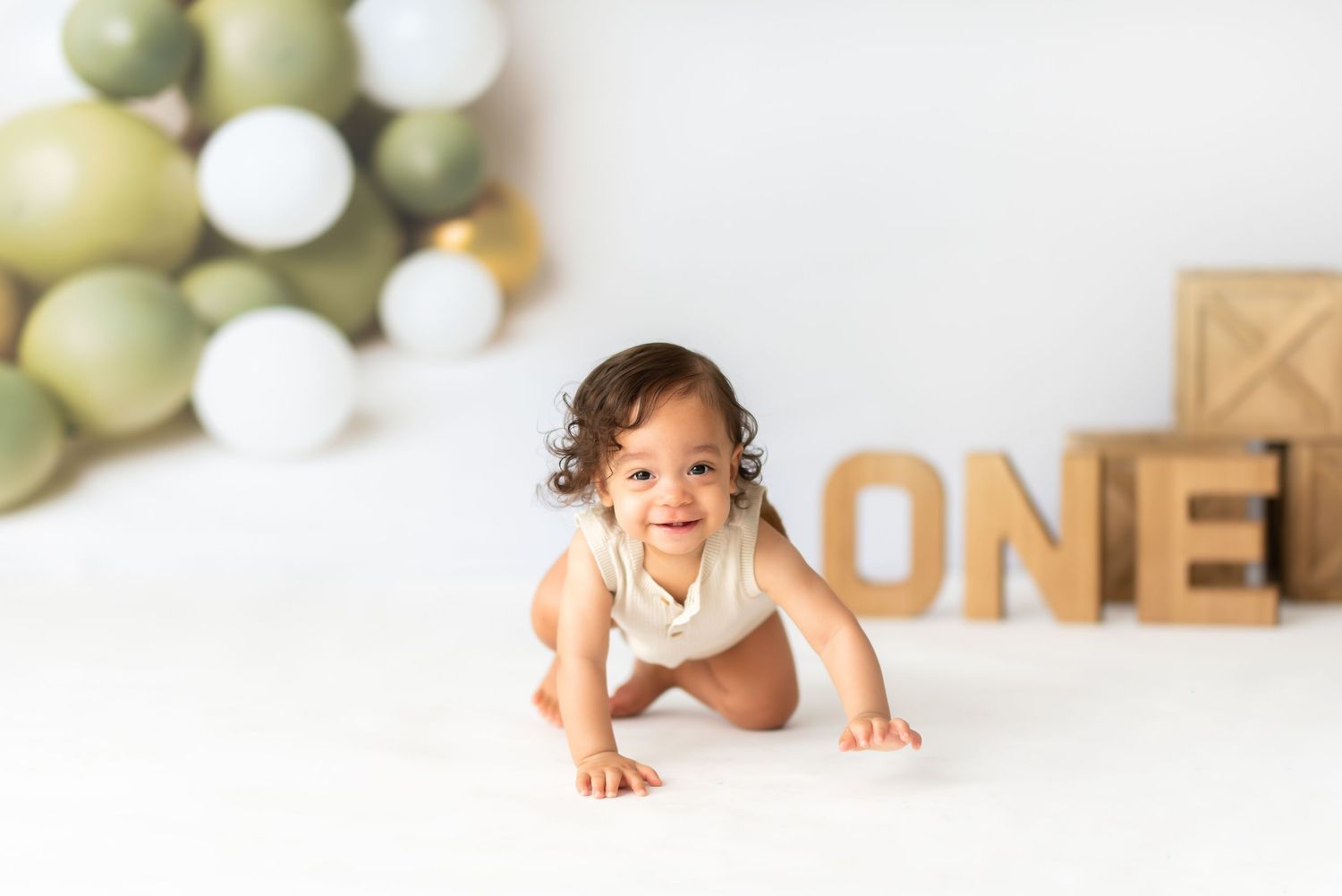 Clean white photography setup with sage and gold balloon decorations.