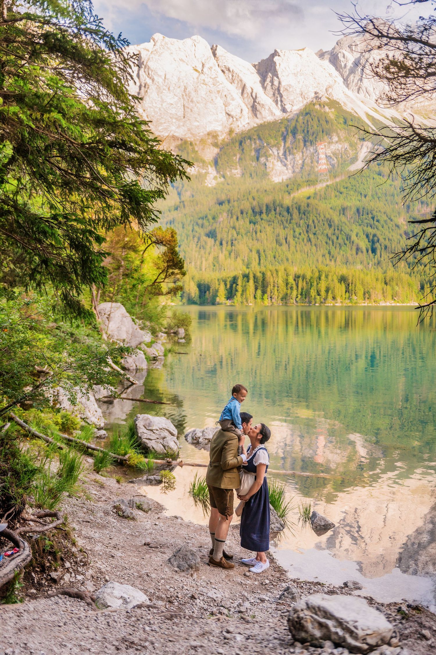 Two people admiring the turquoise alpine lake surrounded by majestic mountain peaks and evergreen forest in nature.