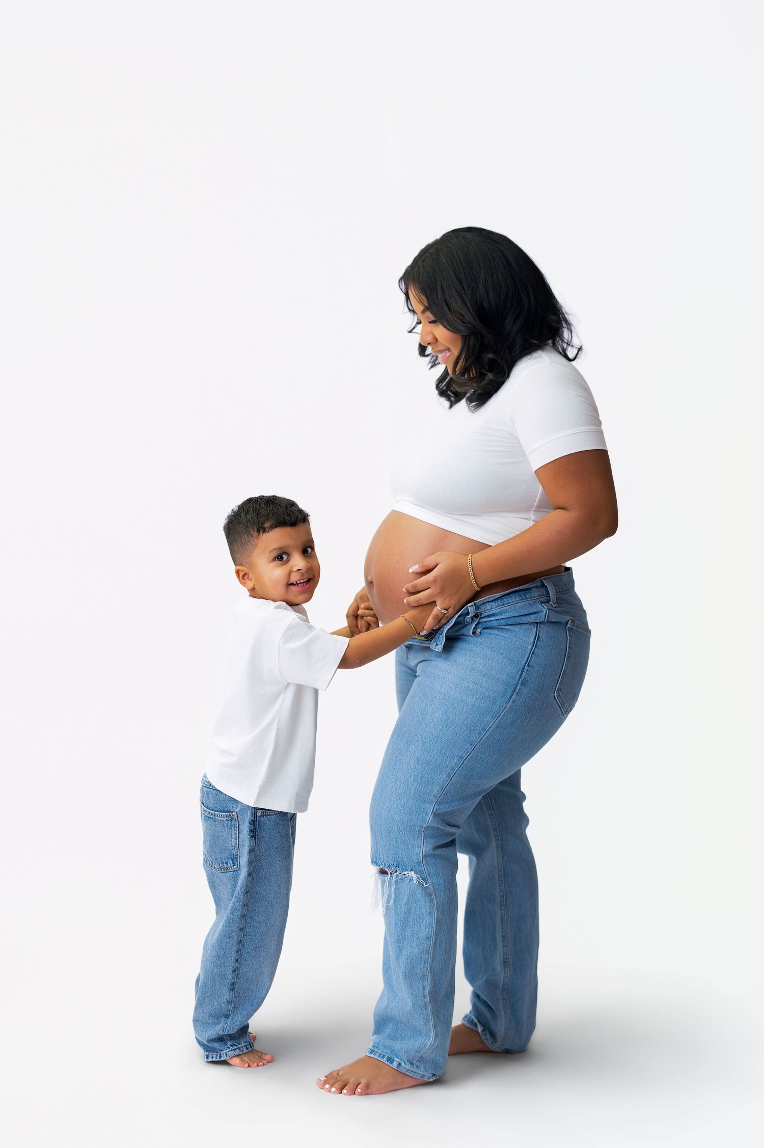 Three sequential images show a parent helping a small child put on pants against a white background.