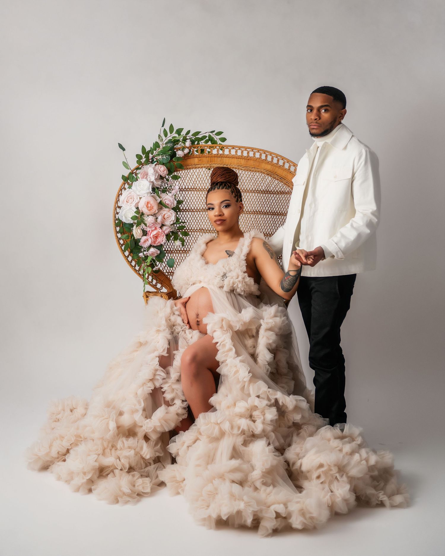 Maternity photoshoot with peacock chair, floral decor, and blush tulle dress.