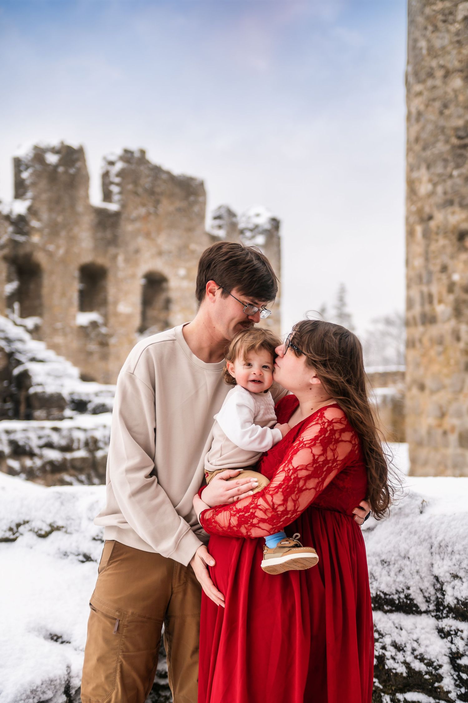 A family shares an intimate moment among snow-covered castle ruins.
