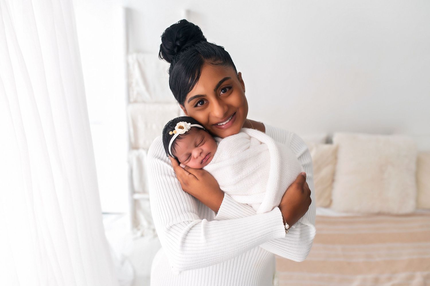 Tender moment with baby wrapped in white against neutral background.
