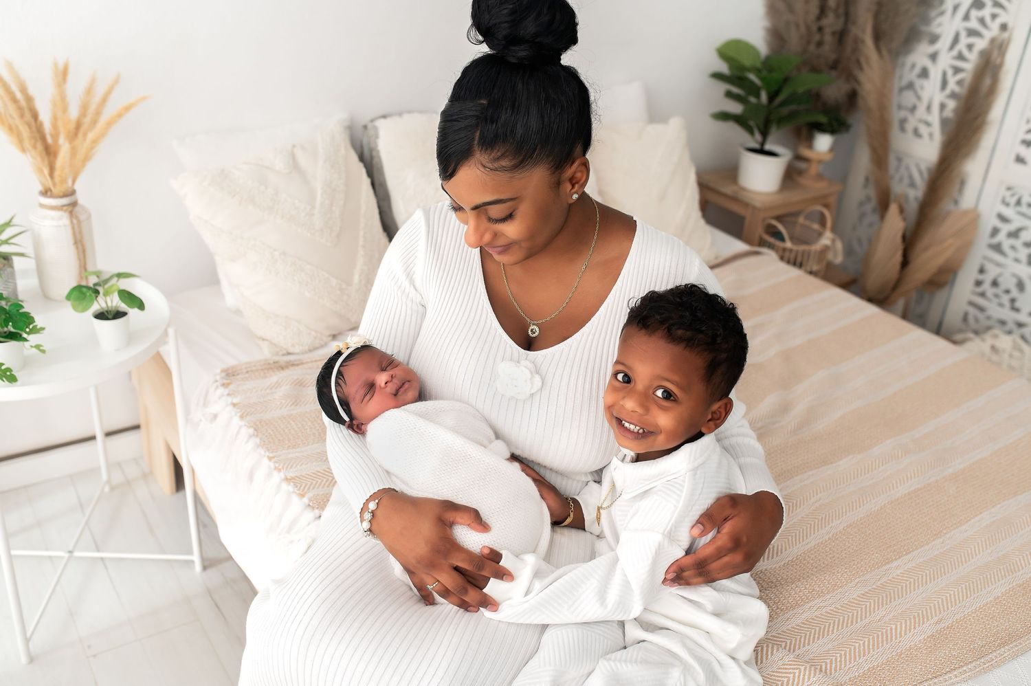Professional newborn photography session with baby and parent in white studio setting.