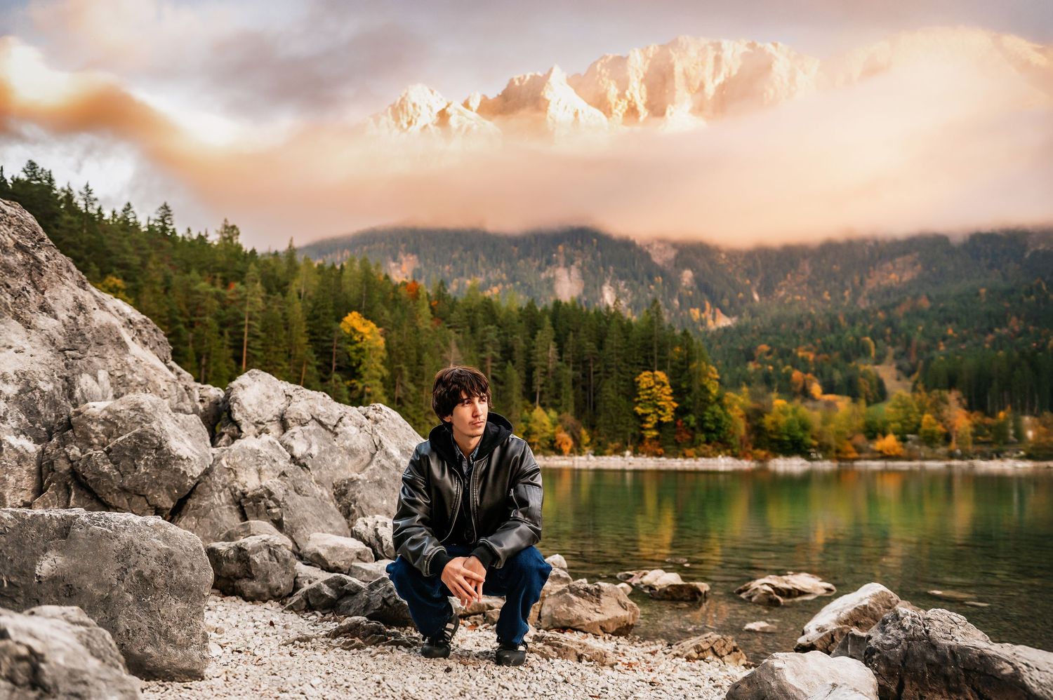 A scenic autumn view of a mountain lake surrounded by rocky shores and colorful fall foliage in the background.
