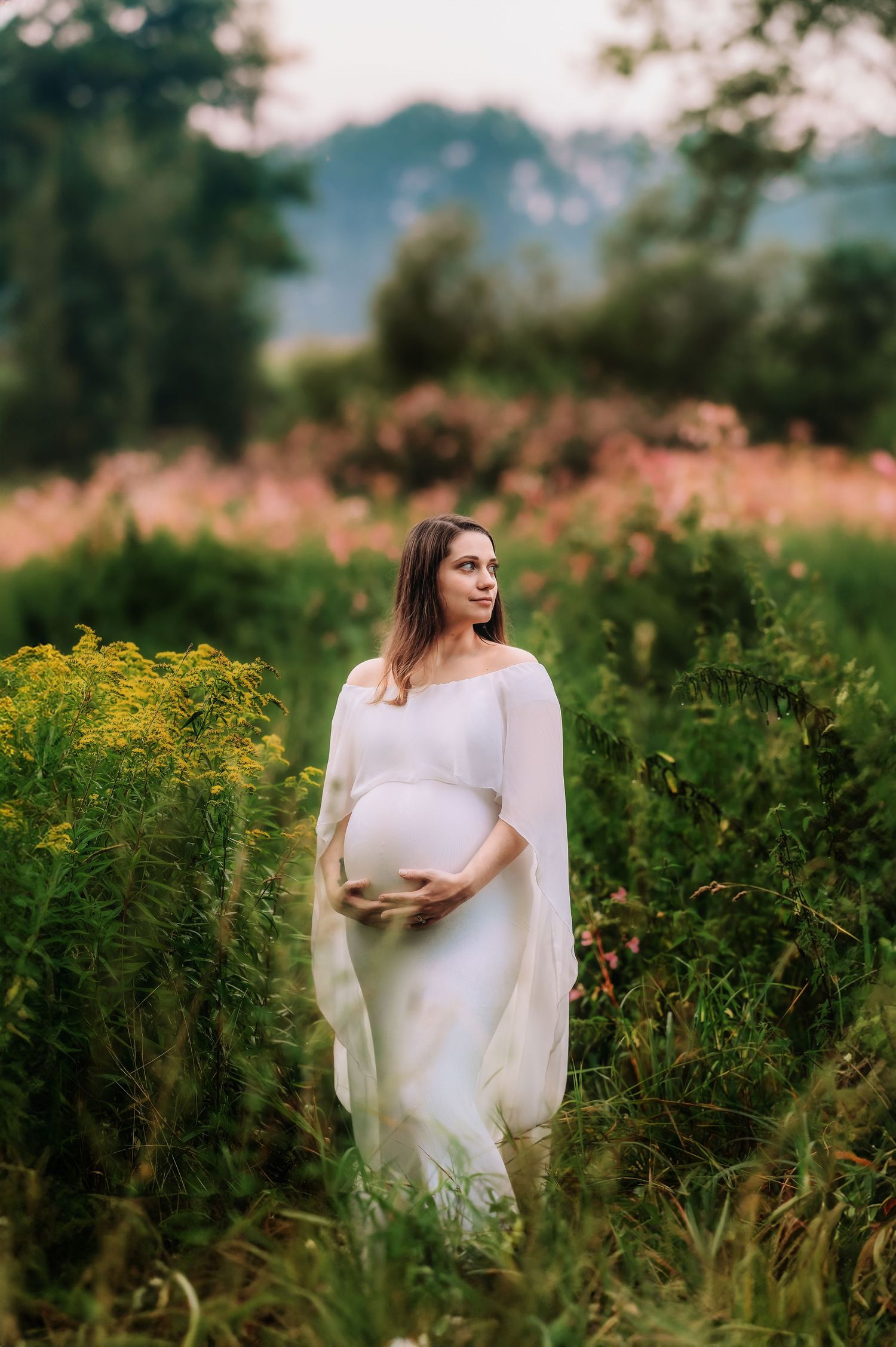 Ethereal maternity photos in a wildflower meadow with flowing white dress.
