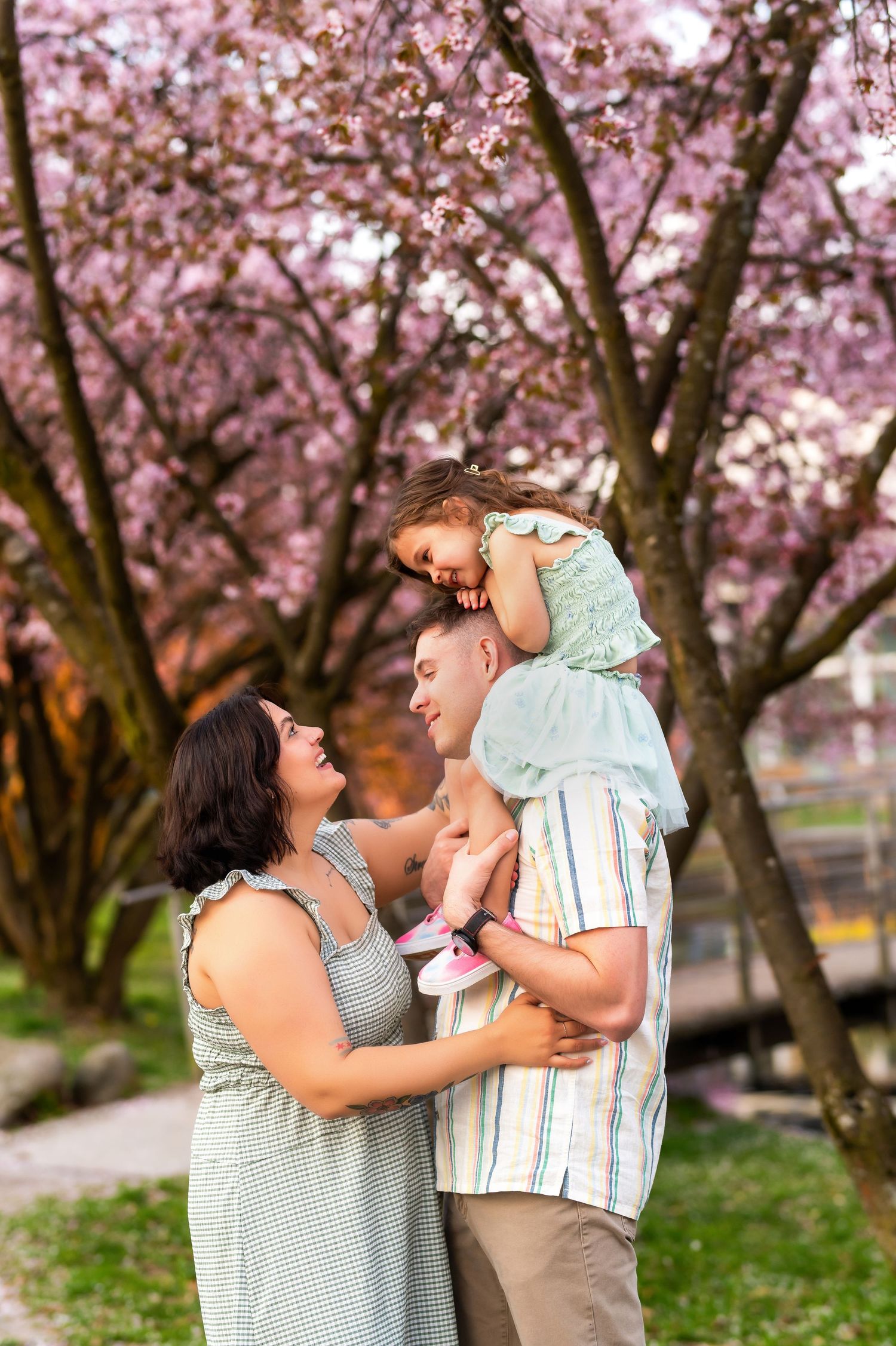 Family sharing joyful moments under pink cherry blossom trees in a spring garden setting.