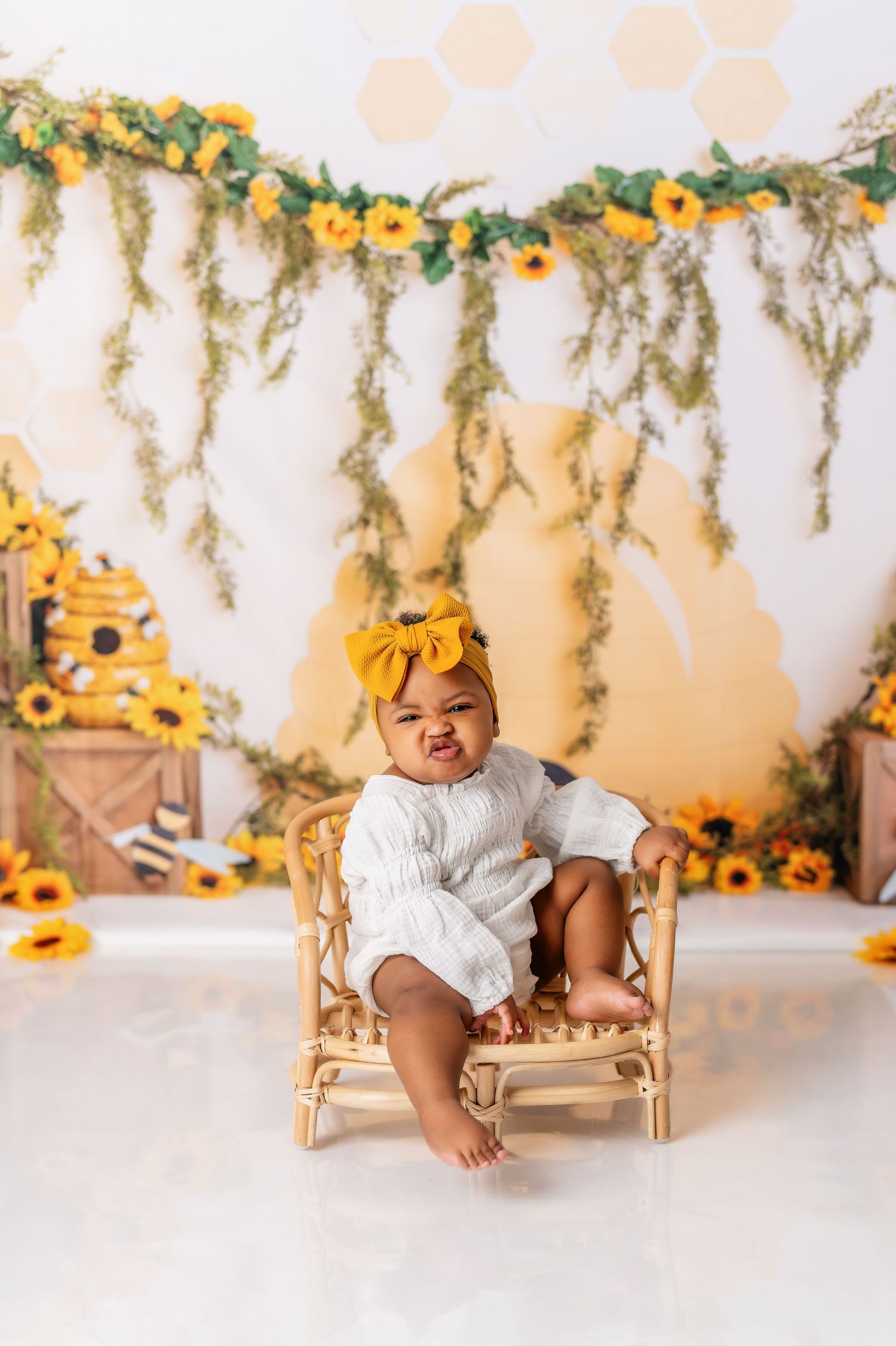 Rustic sunflower themed first birthday photo session with wooden bench and floral garland.