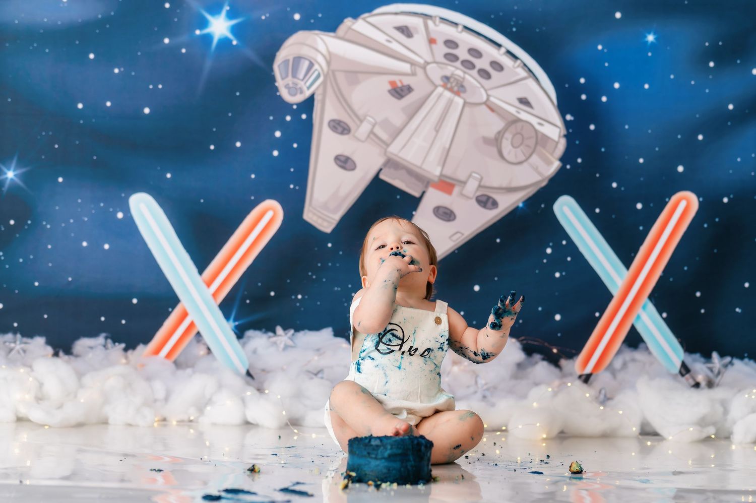 Star Wars themed first birthday setup with spacecraft and lightsaber decorations.