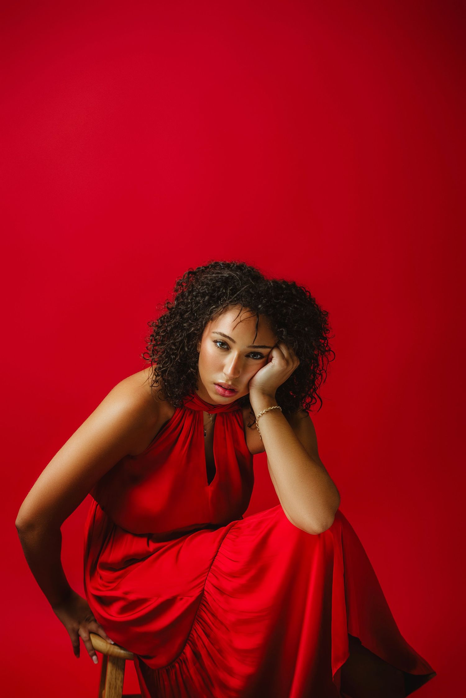 A person in a red flowing dress poses dramatically against a deep crimson background showing artistic movement and emotion.
