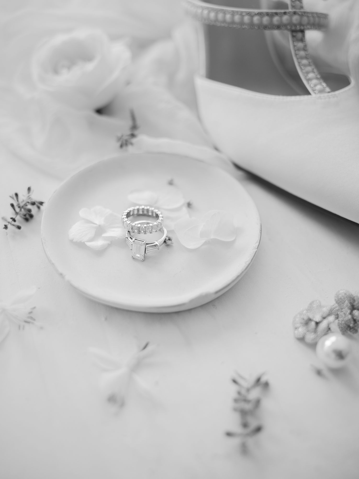 Delicate wedding rings and jewelry details arranged on white plates.