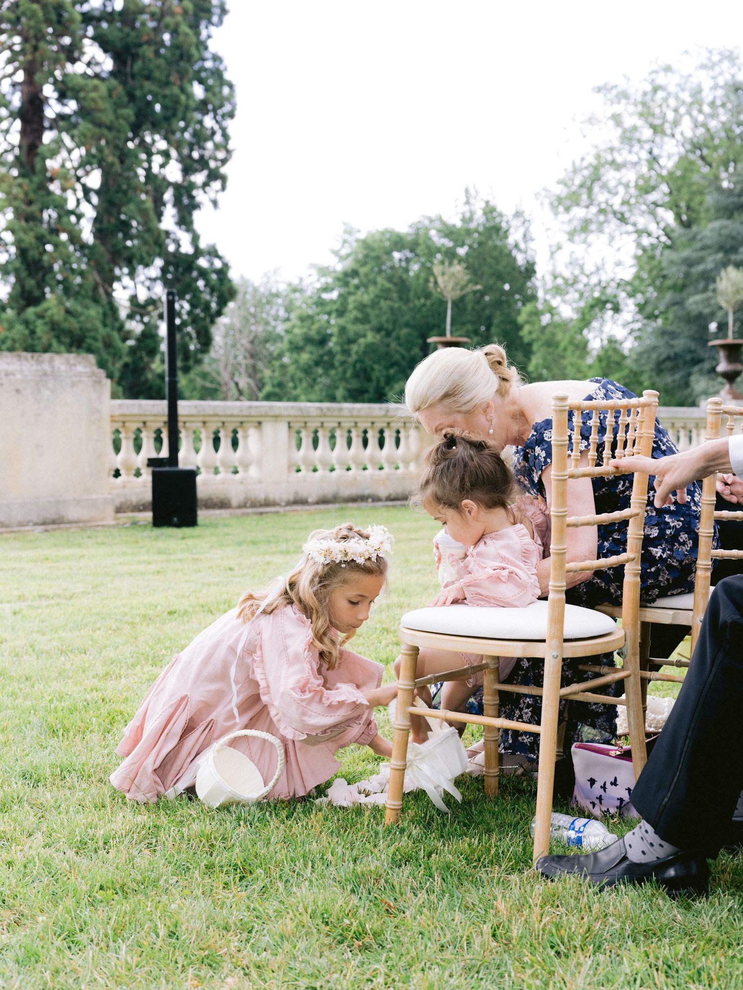 Children in formal attire playing on the grass during an outdoor event.