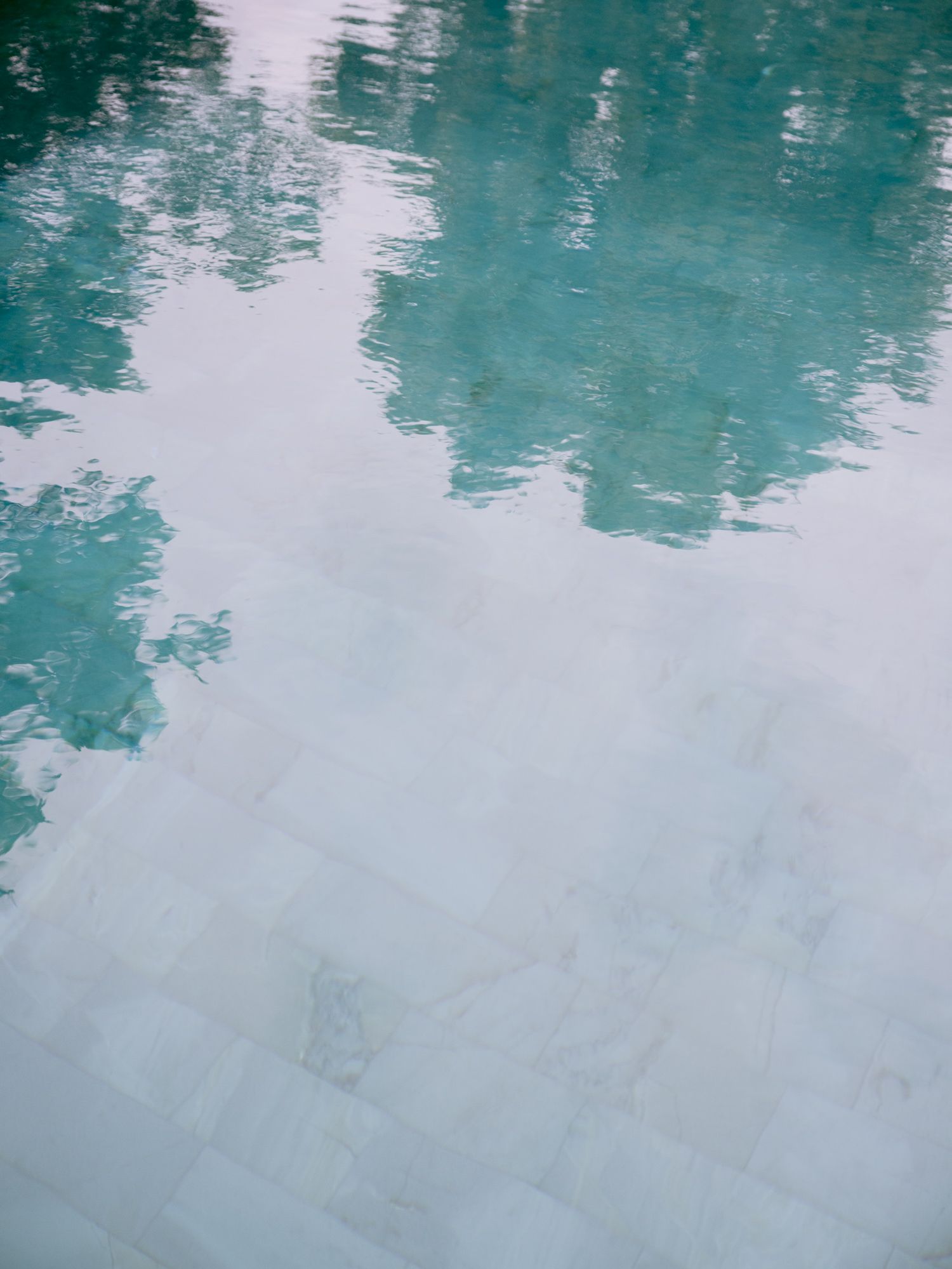 Serene turquoise pool water reflecting light with a rippled surface.