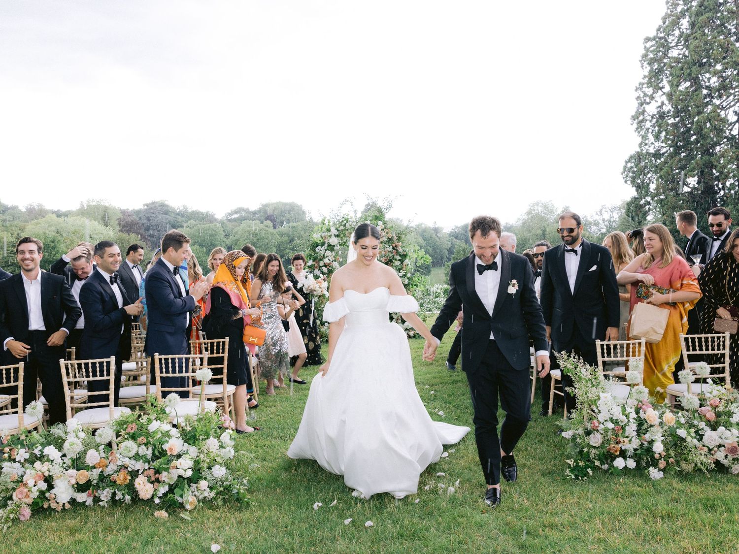 Guests celebrating at an elegant outdoor wedding reception with string lights overhead.