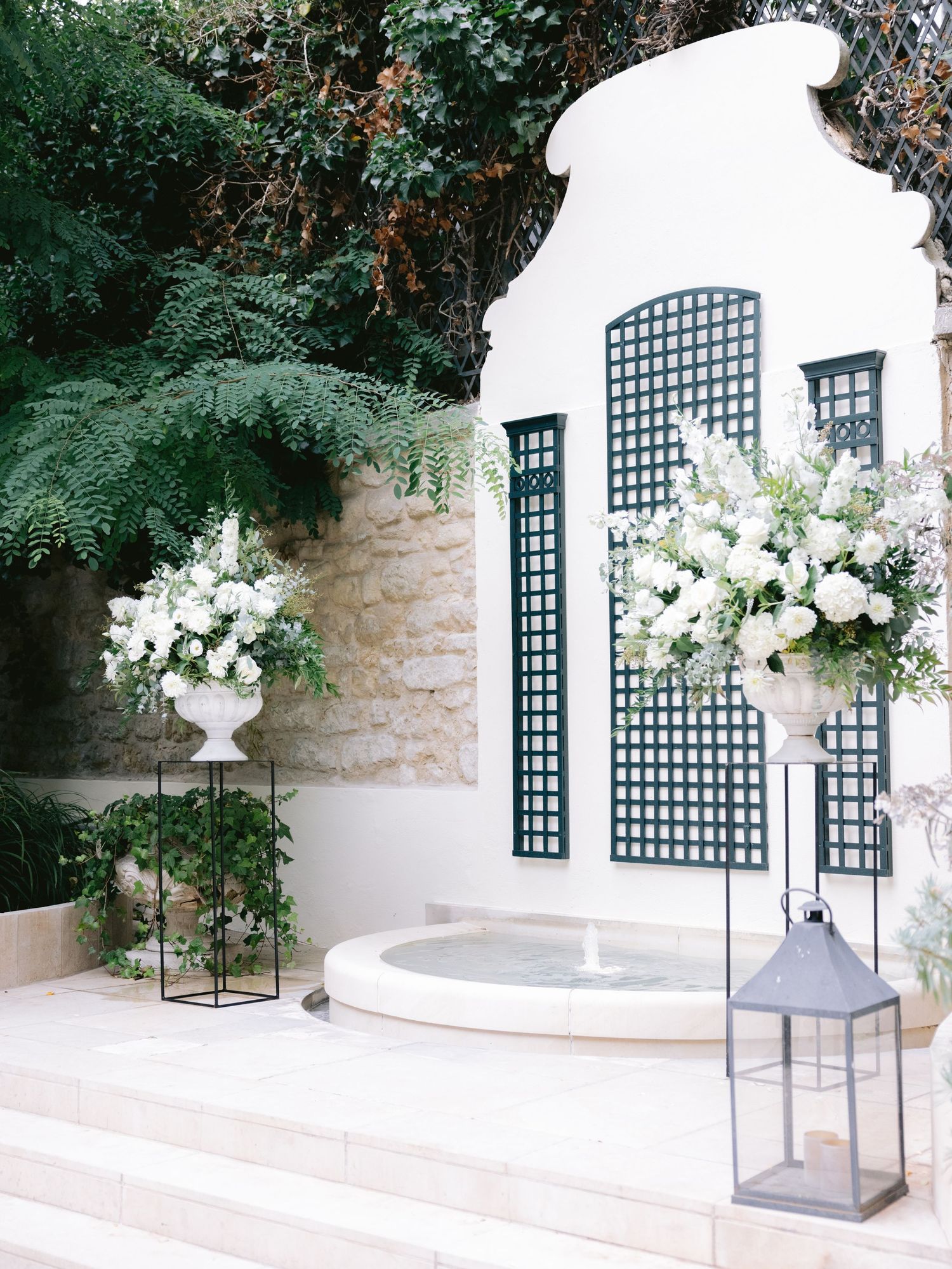 Elegant outdoor wedding ceremony space with white floral arrangements and lantern decorations.