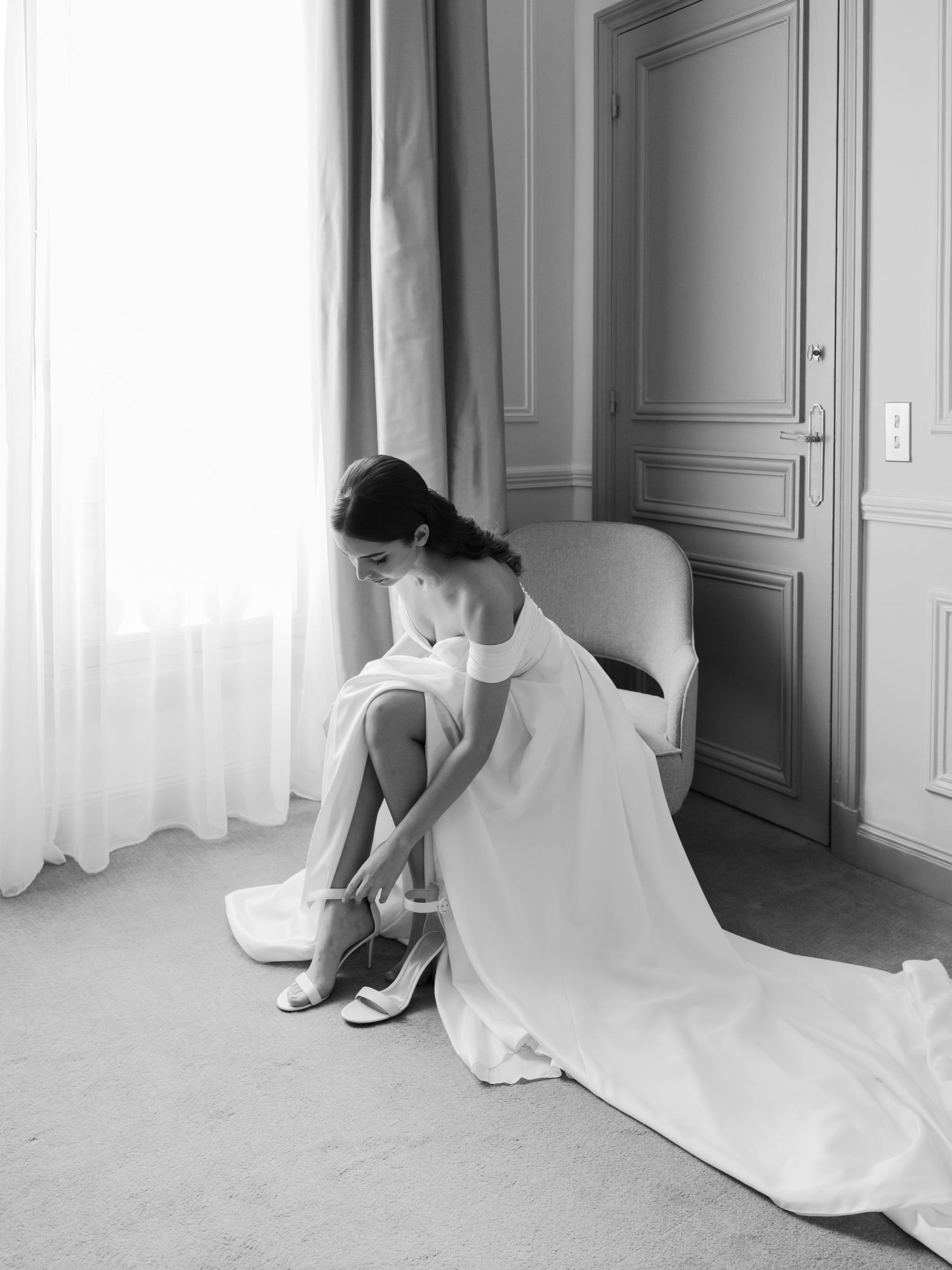 Wedding dress flowing on floor near window in elegant room.
