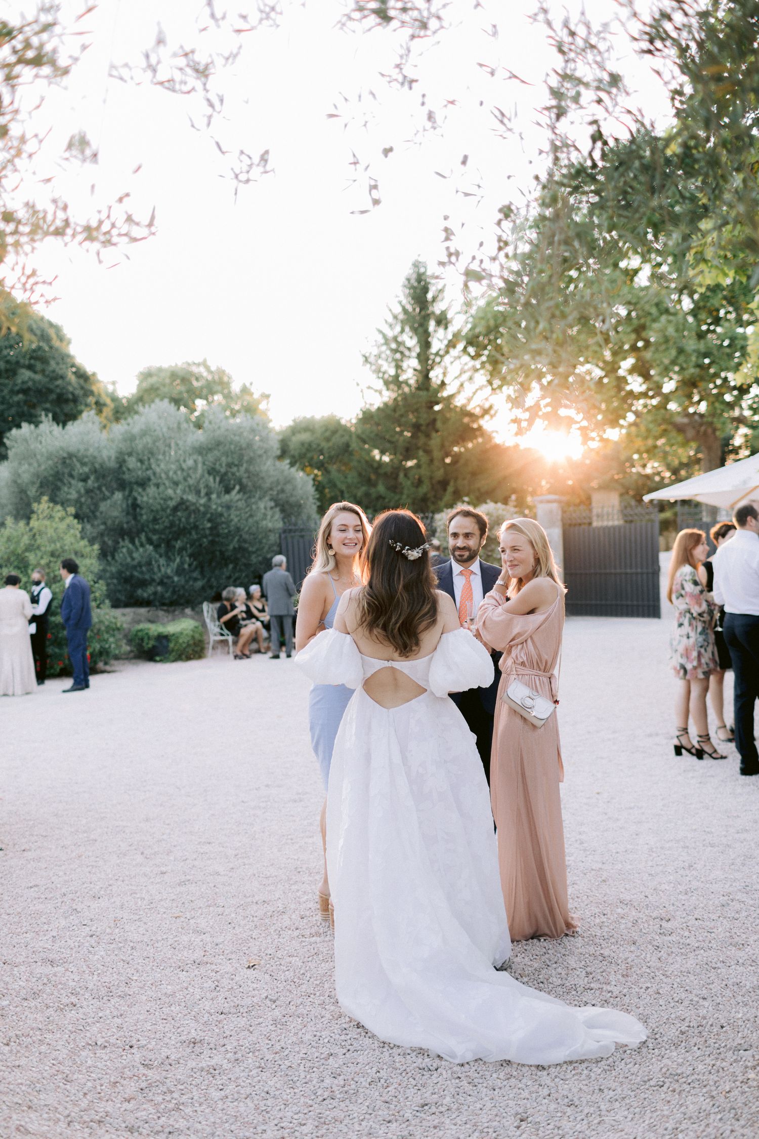 Sunset wedding reception with guests mingling on a light-colored gravel courtyard.