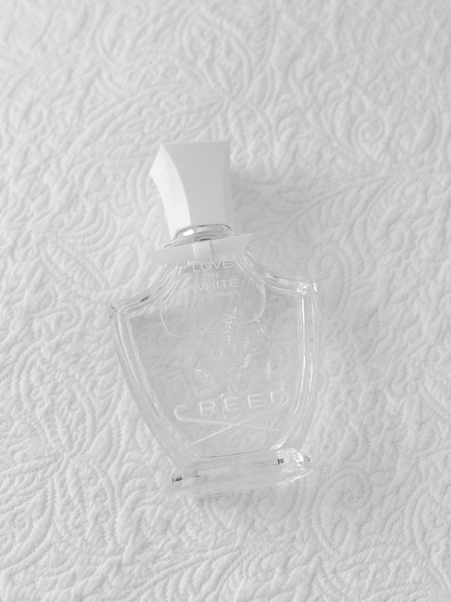 Clear glass perfume bottles arranged on white textured background.