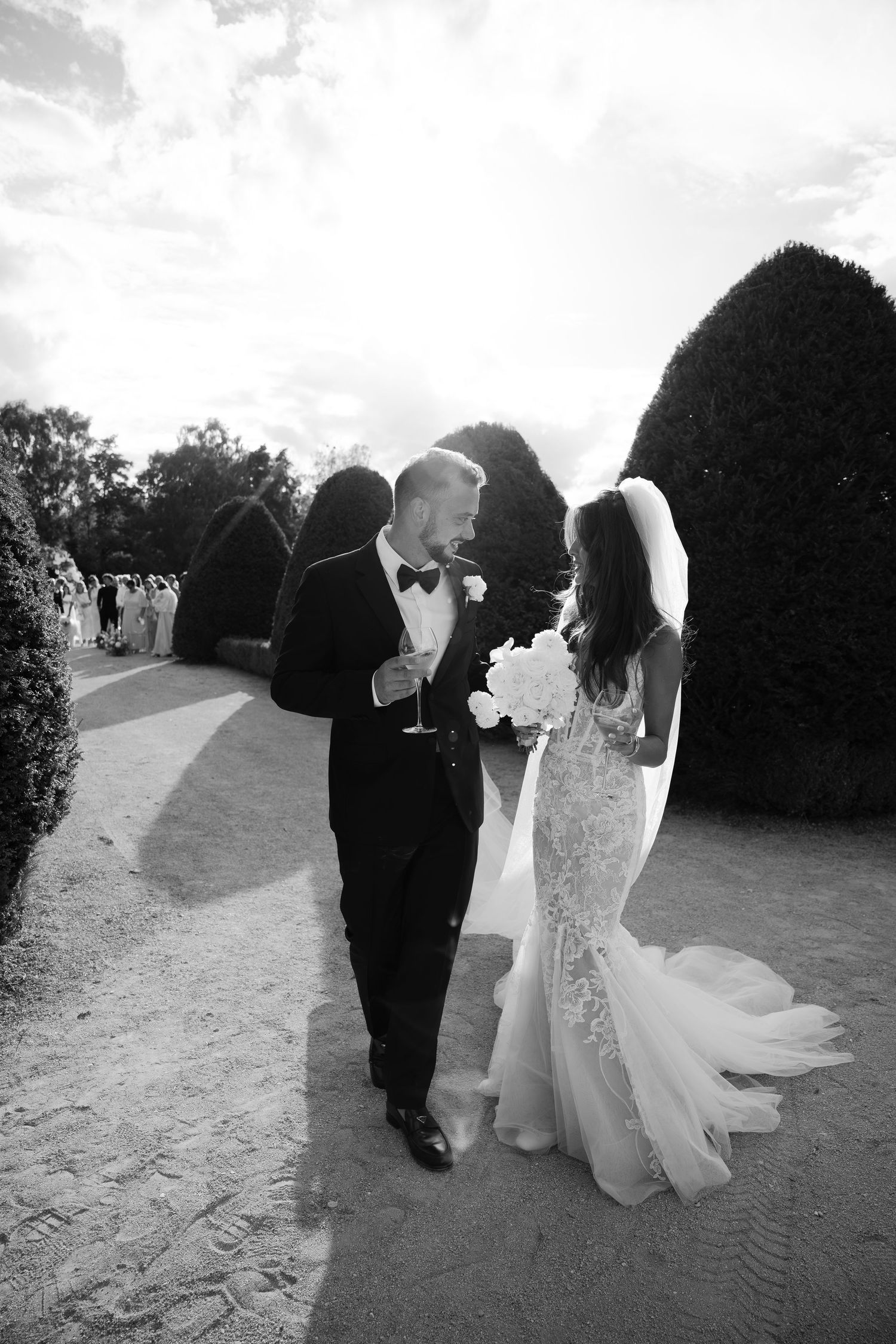 Black and white wedding photo capturing romantic moments on a garden path at Château de Sept Saulx