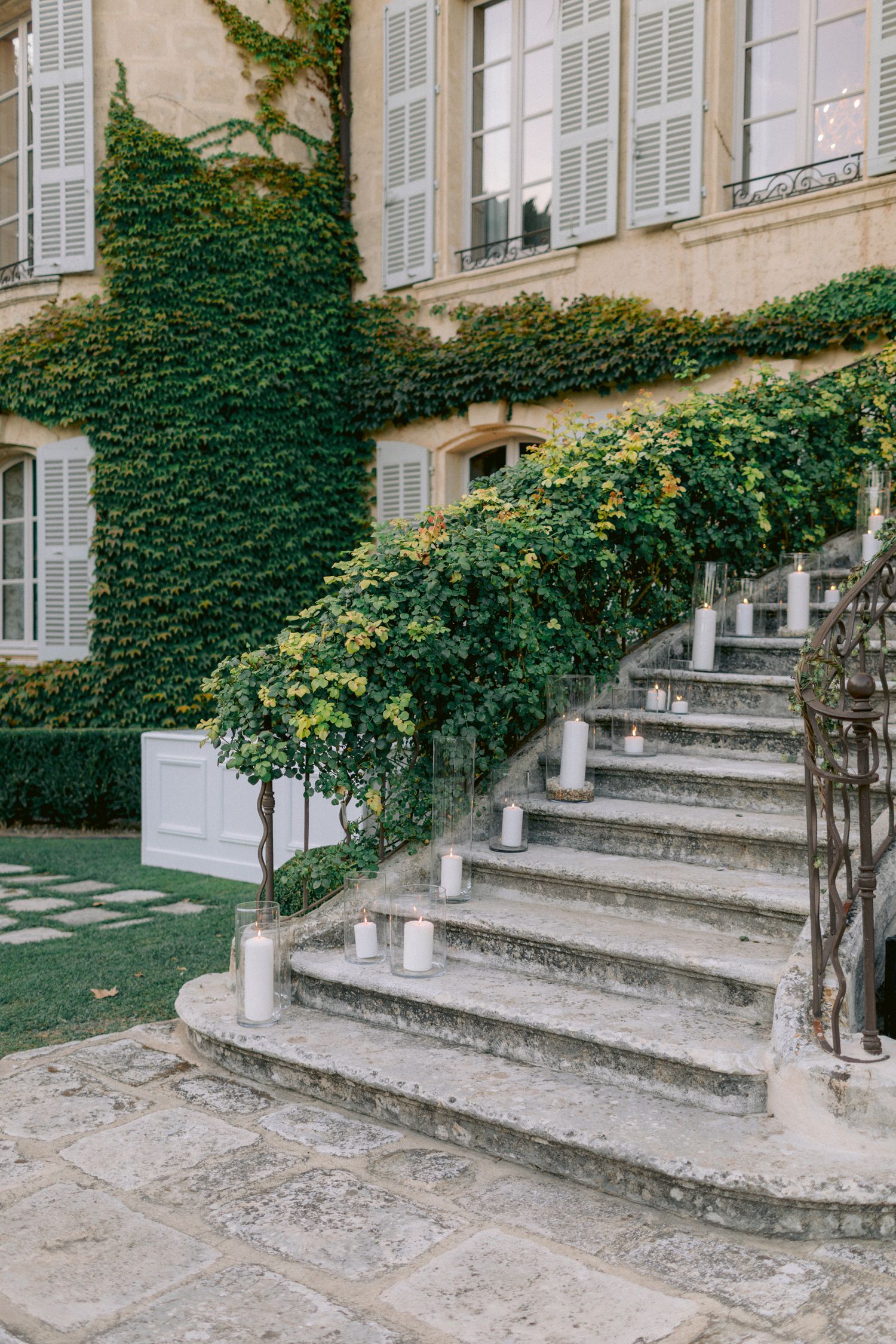 Stone steps with ivy covered walls leading to an elegant French chateau entrance.