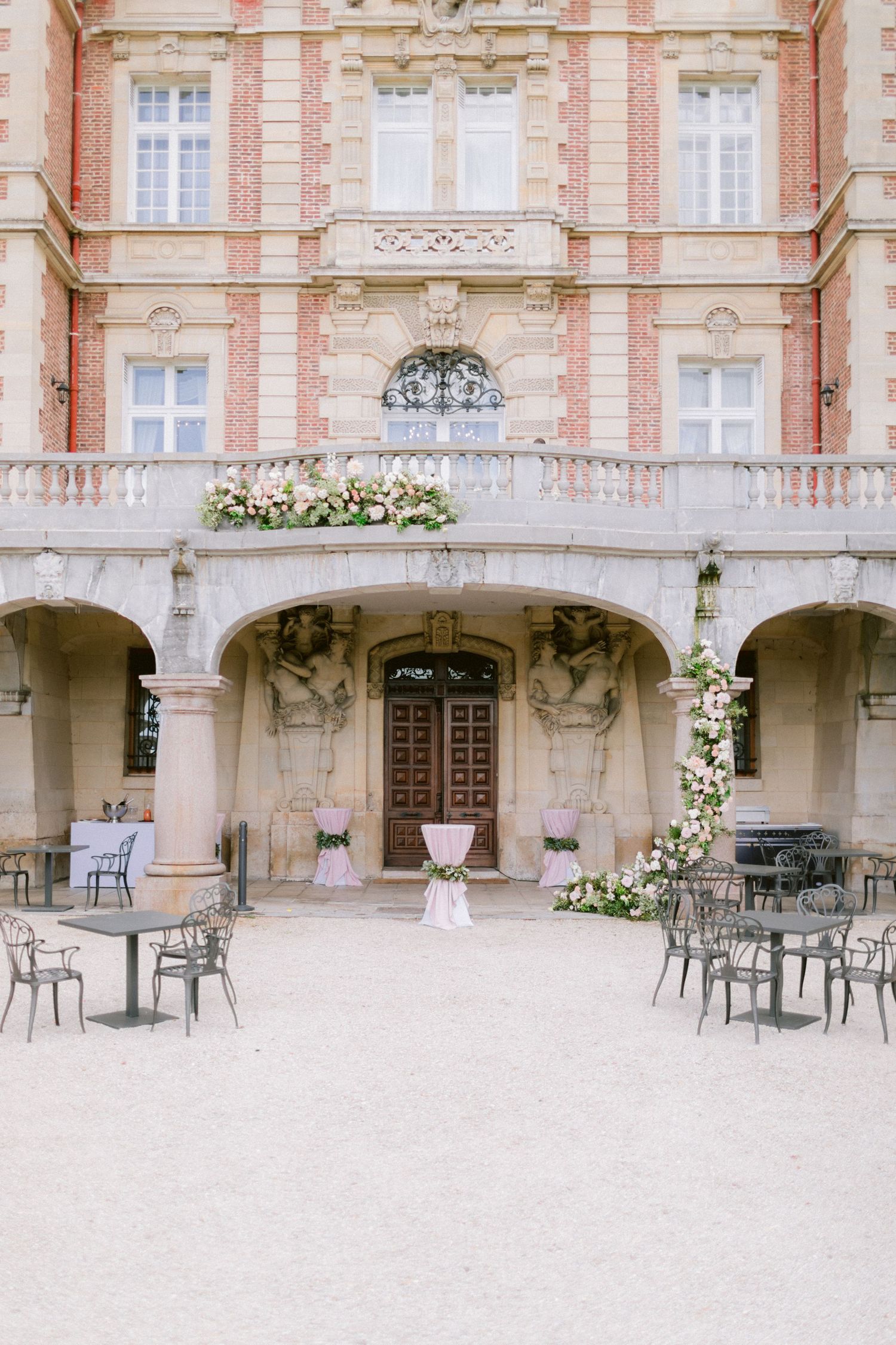 Elegant stone courtyard with pink and white wedding decor and scattered bistro tables.