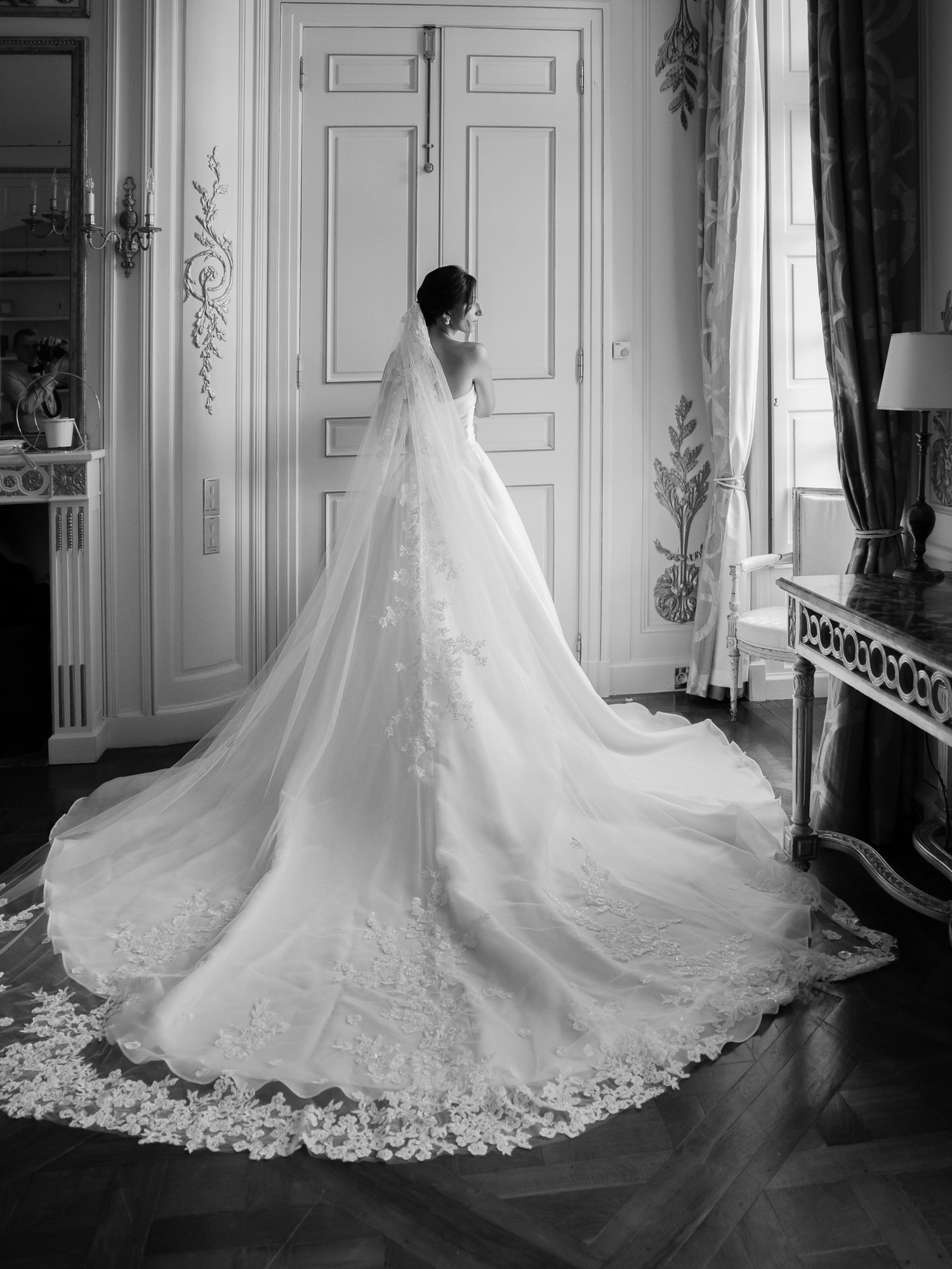 Stunning lace wedding gown with cathedral train displayed in an elegant room.