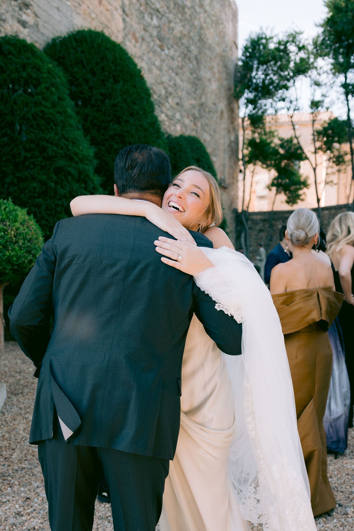 Wedding guests embracing and celebrating during outdoor reception.