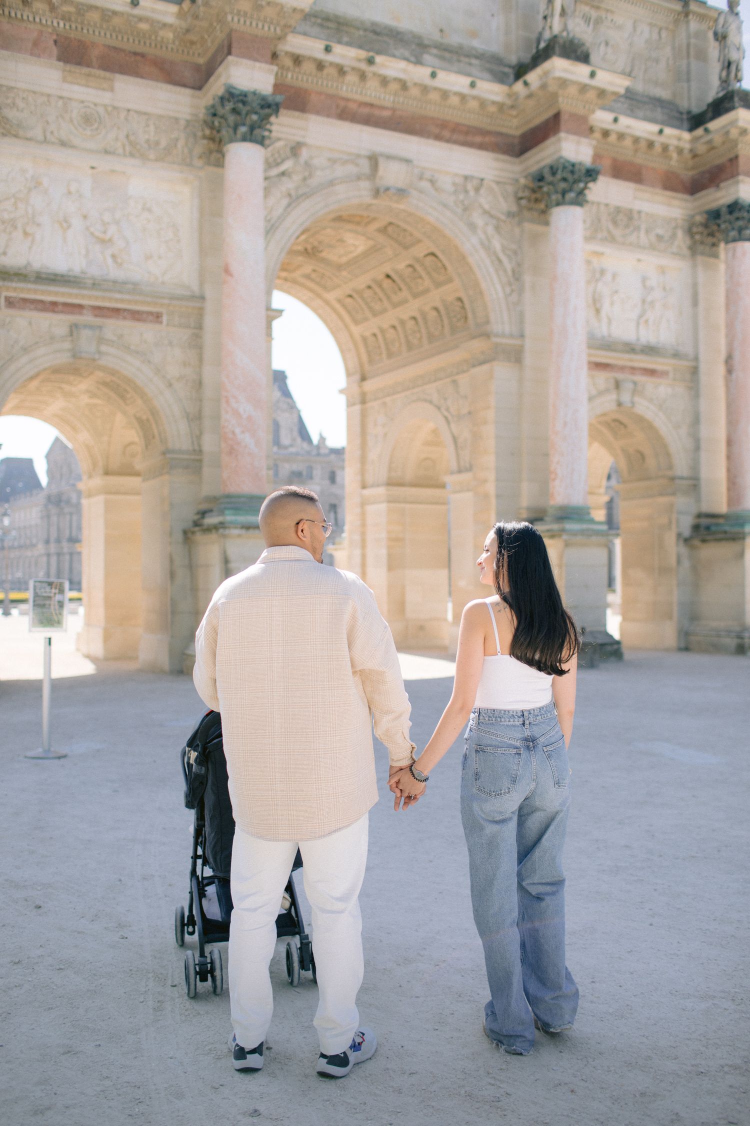 People walking through elegant stone archways and columns of historic building.