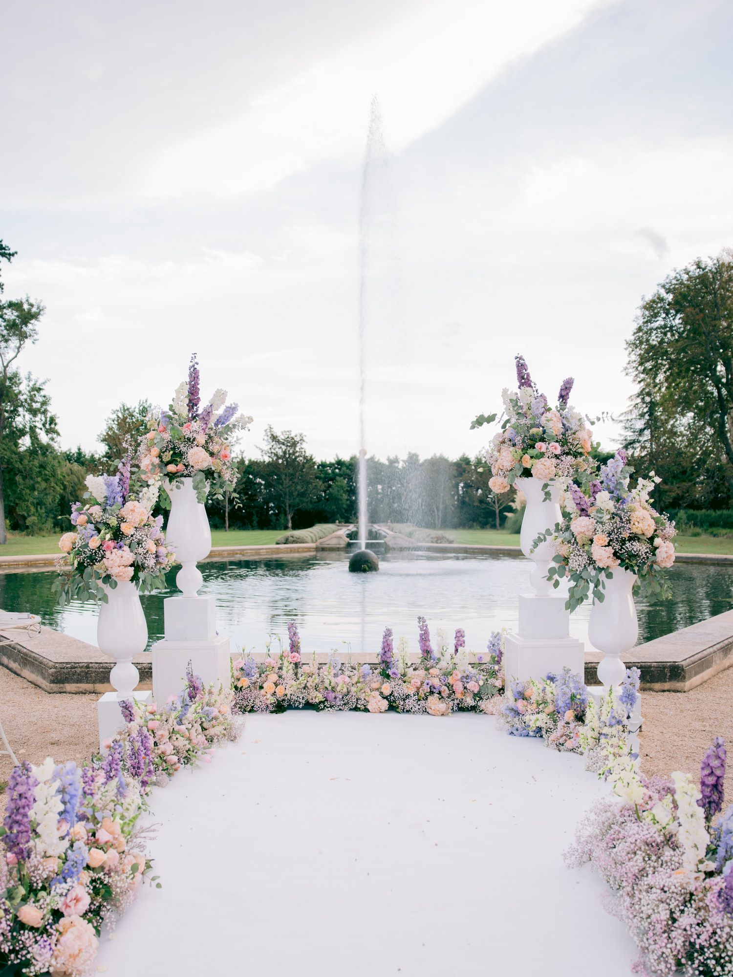 Elegant wedding arch decorated with pink and purple flowers against a white backdrop.