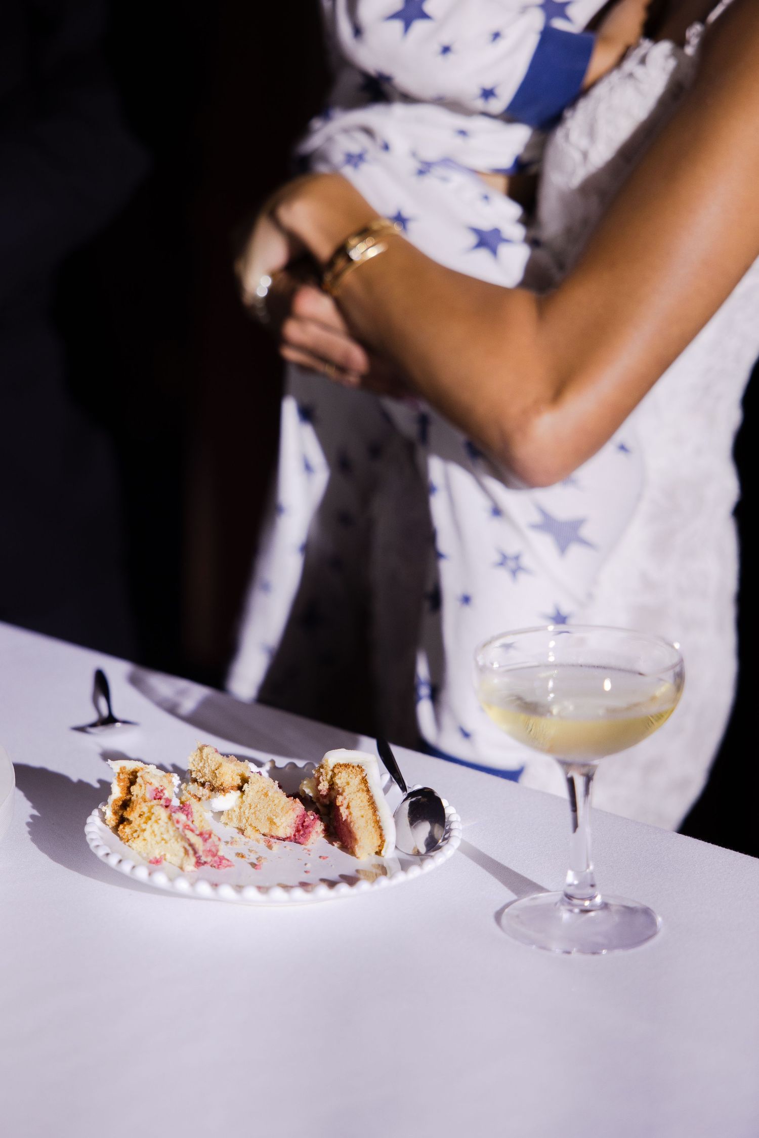 Wedding reception place setting with dessert and champagne on a white tablecloth.