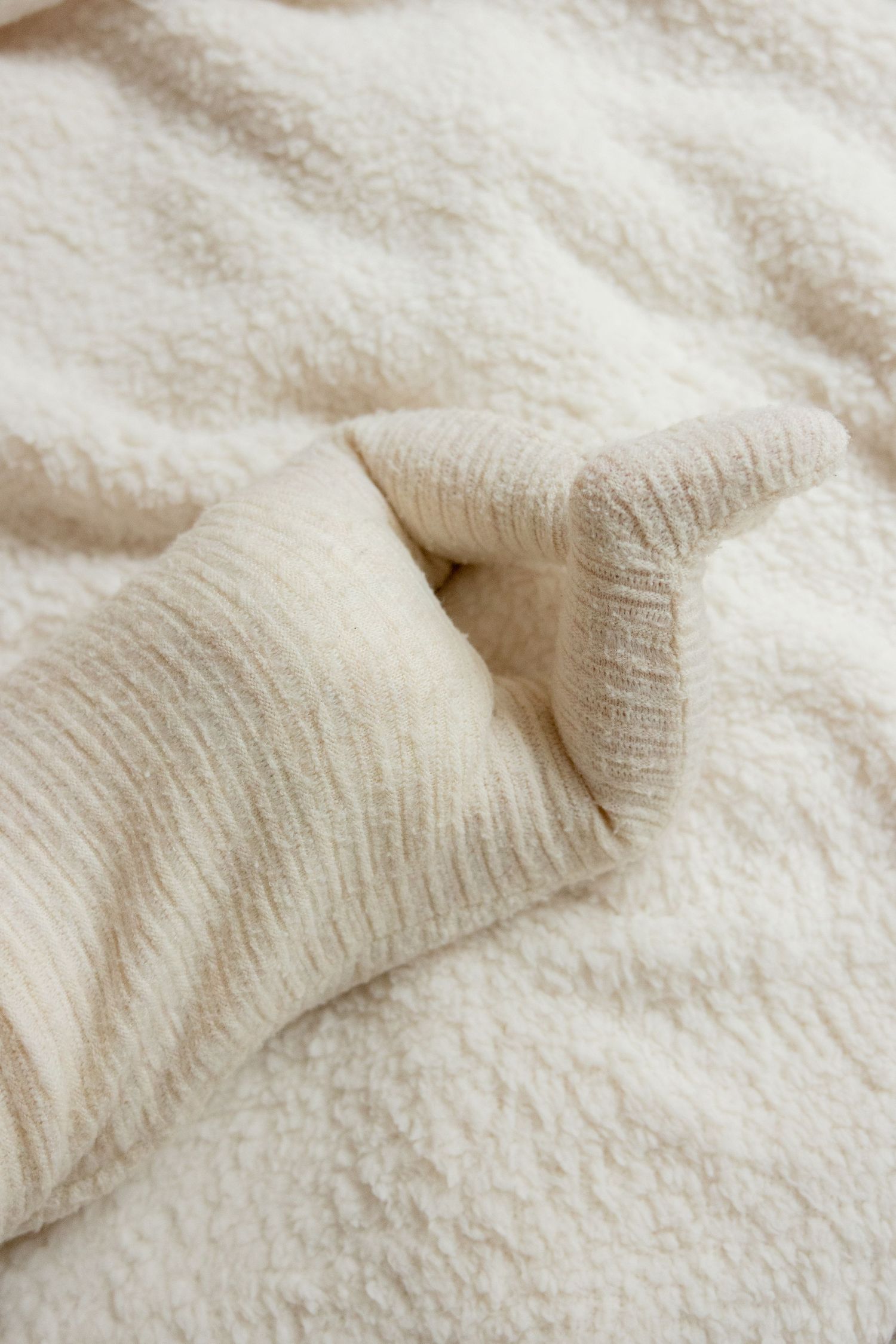 Close-up texture shots of cream colored knit fabric with soft folds and patterns.