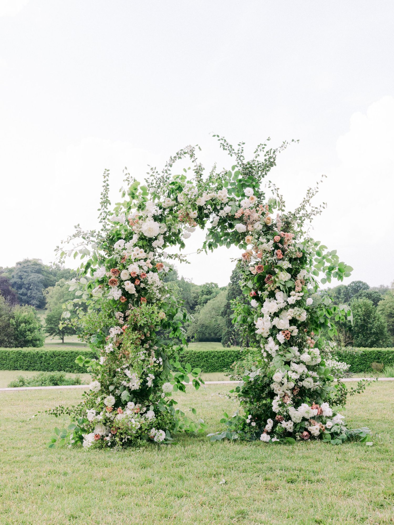 Beautiful floral arrangements with pink and white blooms create an enchanting garden arch display.