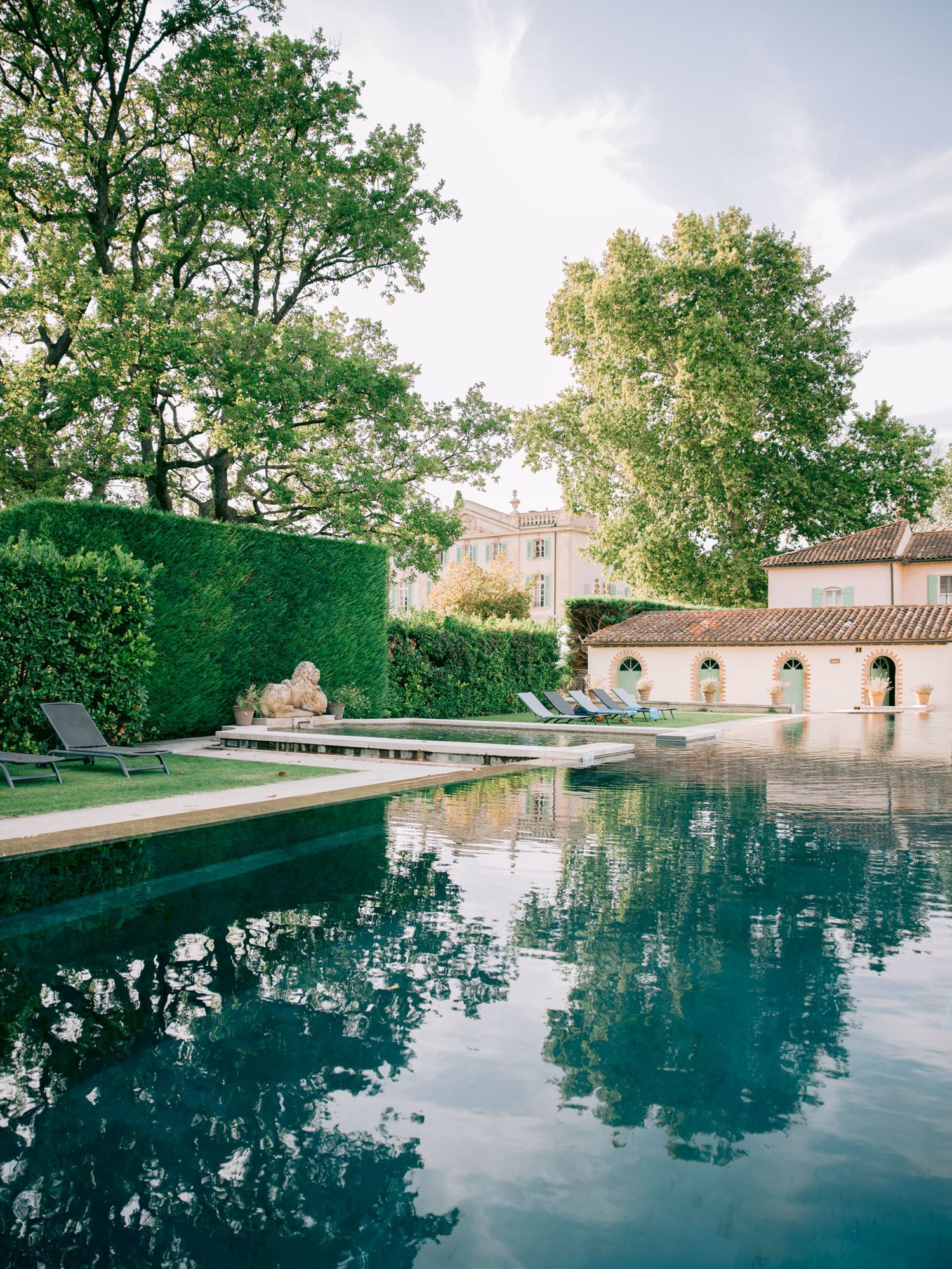 Luxurious swimming pool reflecting trees and architecture in a grand estate setting.