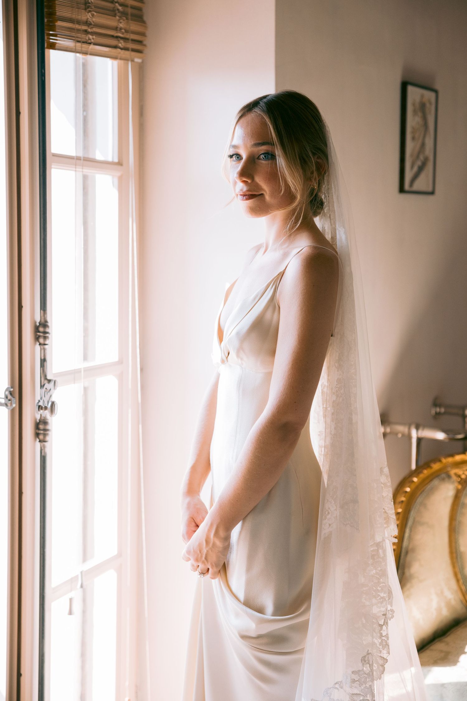 Elegant bridal portrait by window with soft natural light streaming in.
