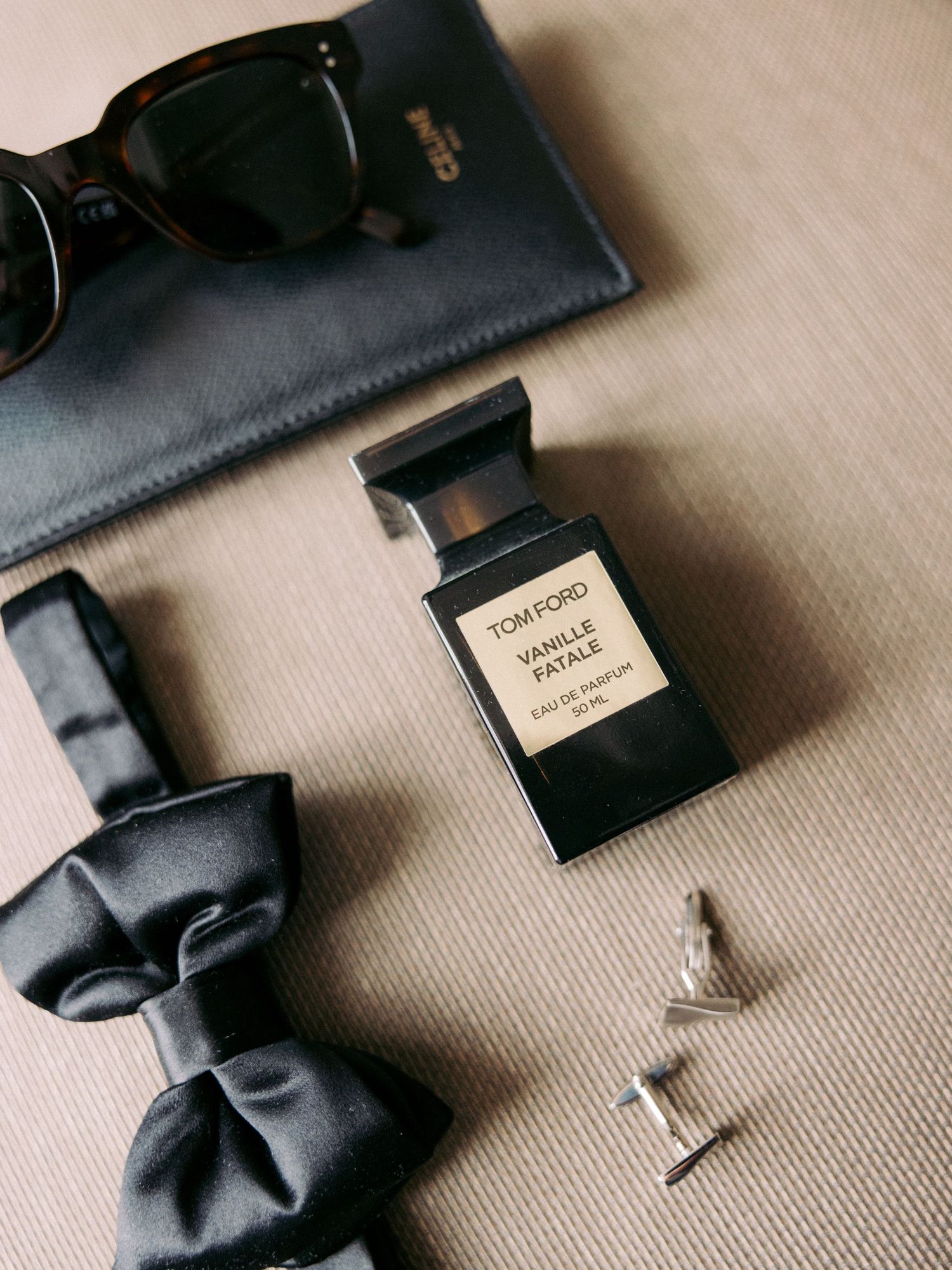 Black bow tie and accessories arranged on a beige surface.