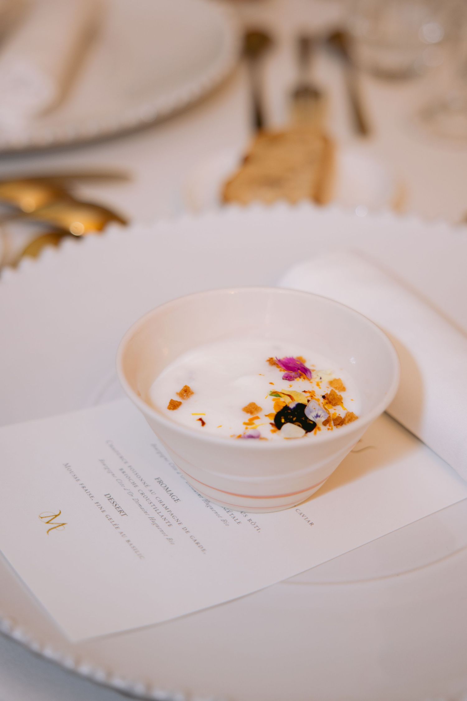 Delicate floral garnishes adorn white plates alongside wedding menu cards.